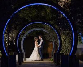 Married couple pose for photo between arches